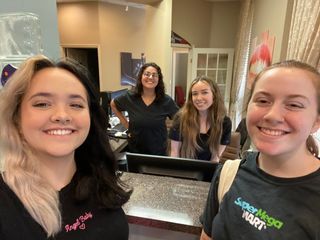 Four people smiling at a reception desk. Two customers with employees in a business interior.