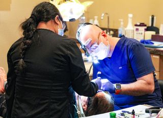 Dentist and assistant working on a patient's teeth in a dental office.