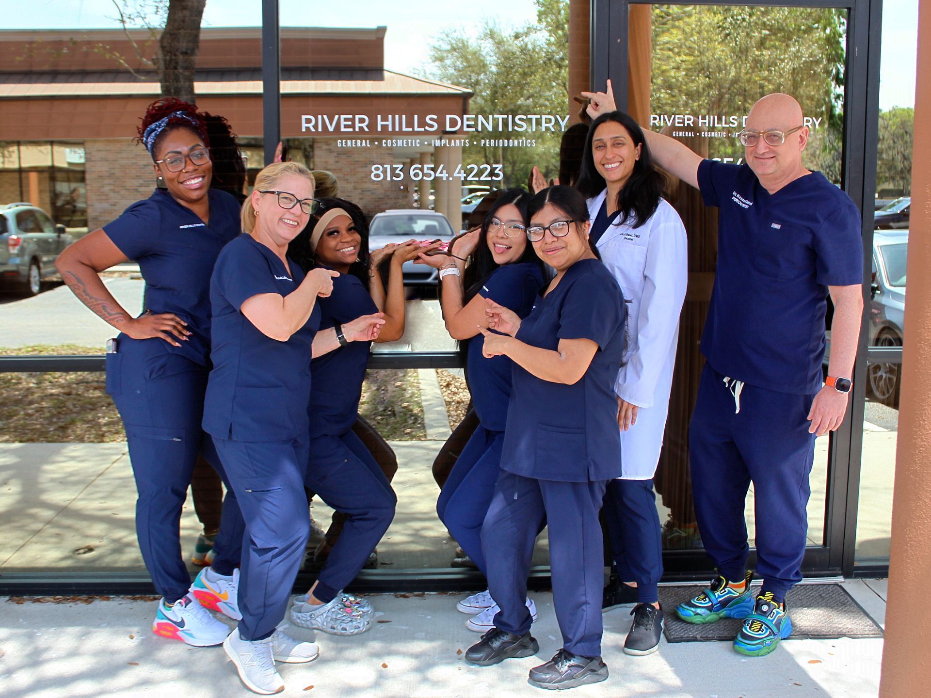 River Hills Dentistry staff posing in navy scrubs outside the office entrance