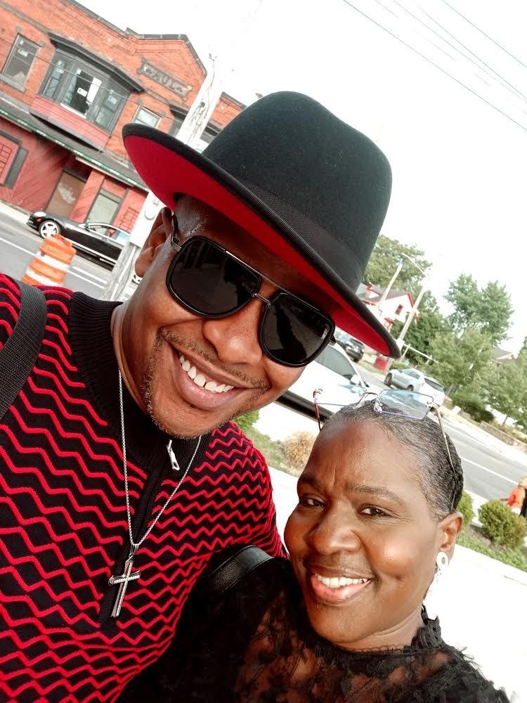 A man wearing a hat and sunglasses is posing for a picture with a woman.