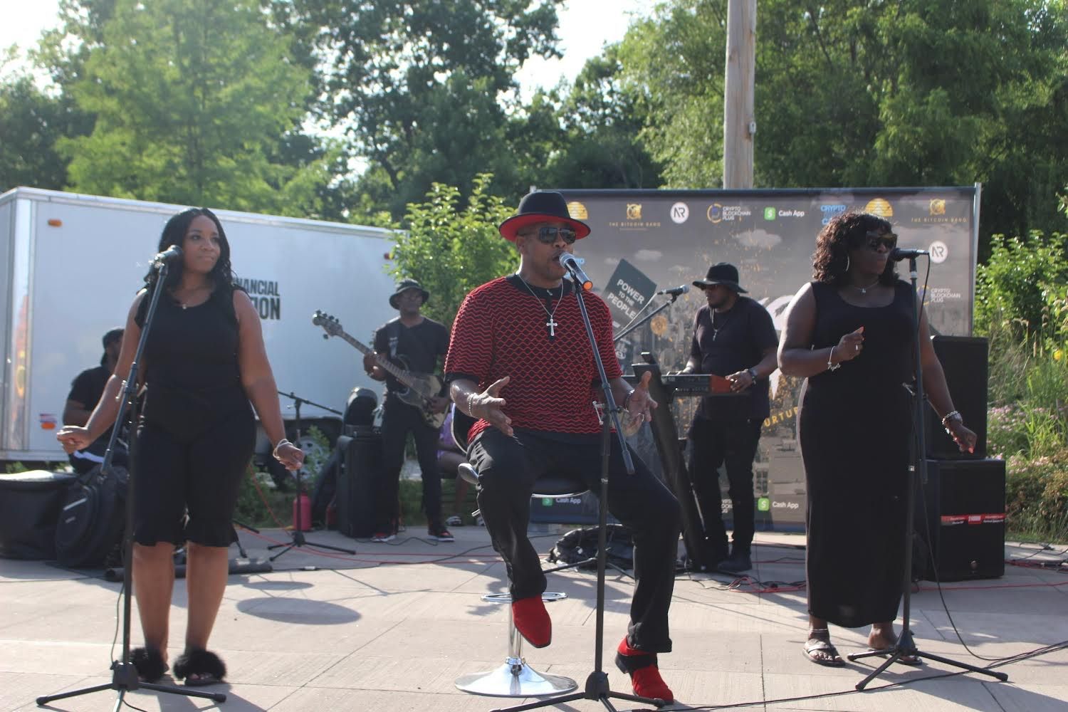 A group of people are playing instruments and singing into microphones on a stage.
