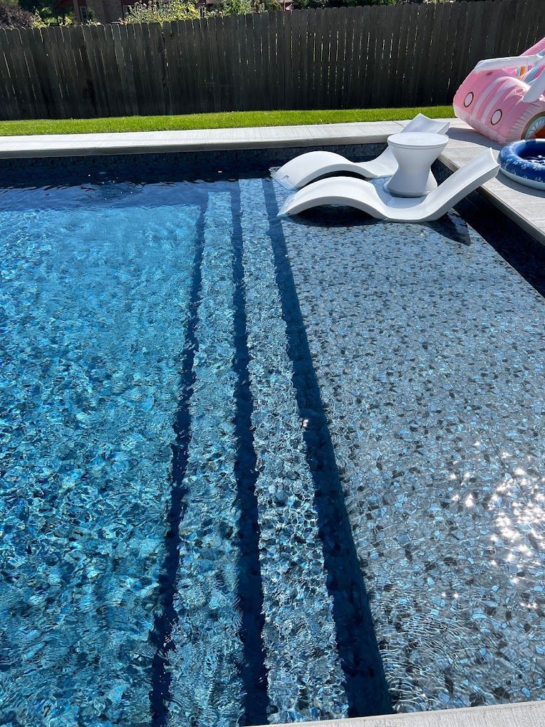 A swimming pool with chairs and a pink float in it.