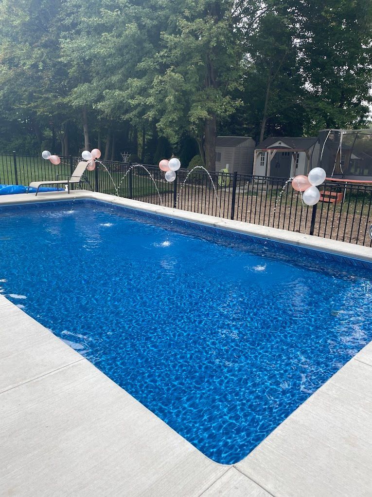 A large swimming pool surrounded by trees and balloons.