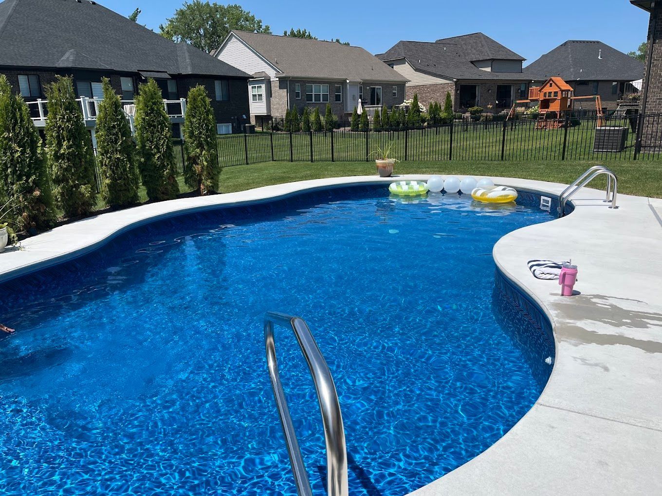 A large swimming pool in a backyard with houses in the background