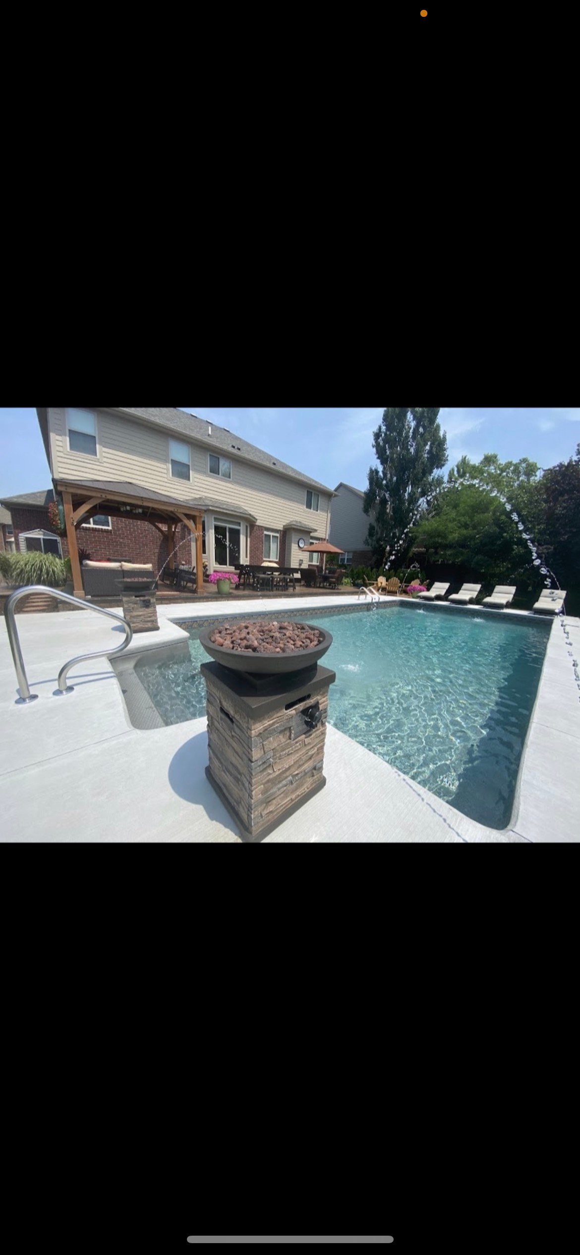 There is a large swimming pool in the backyard of a house.