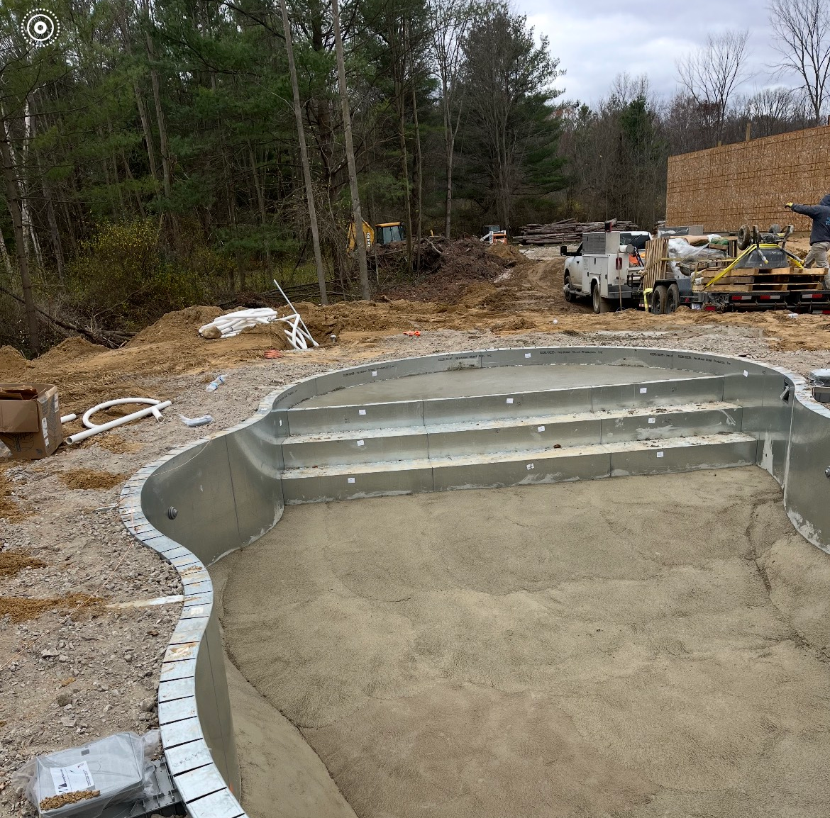 A swimming pool is being built in the middle of a dirt field