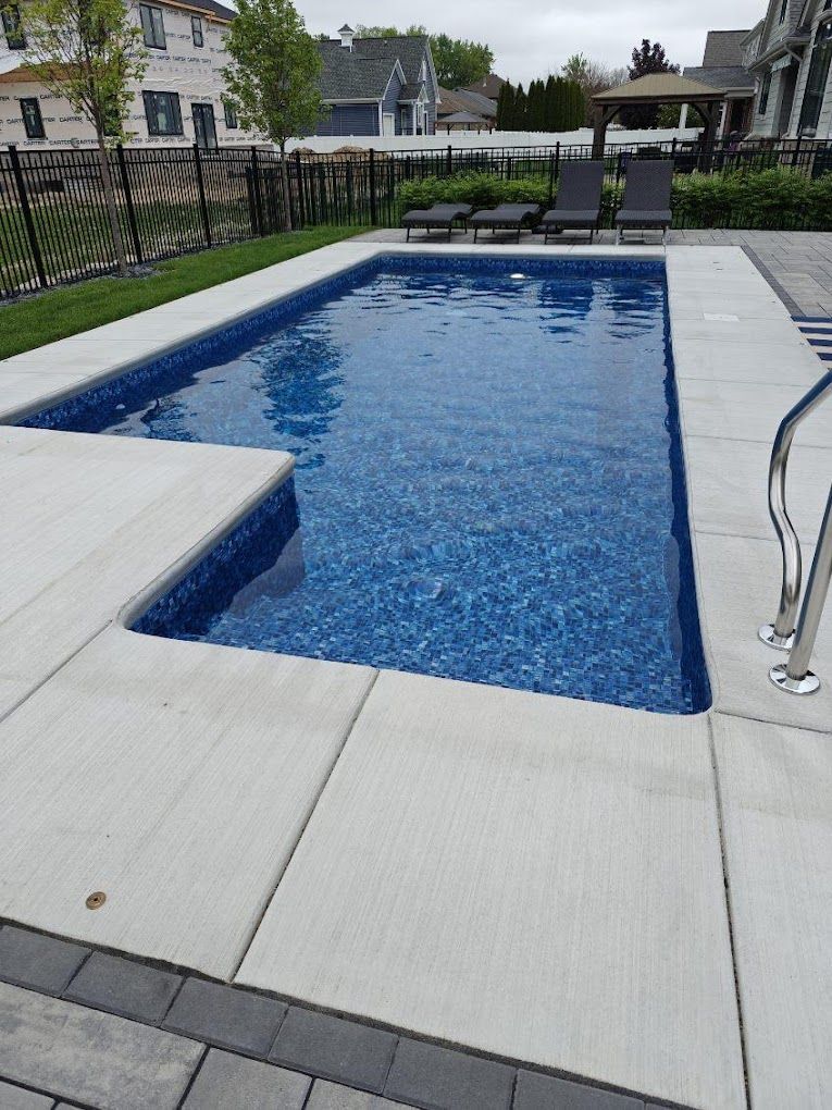 A large swimming pool is surrounded by chairs and a fence.