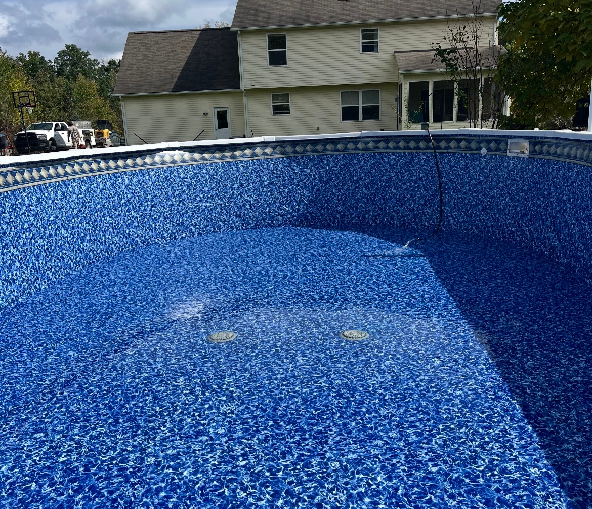 A large swimming pool with a house in the background
