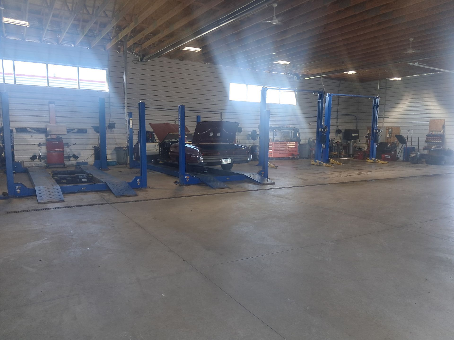 Auto repair shop with several vehicles on blue lifts inside a large garage.