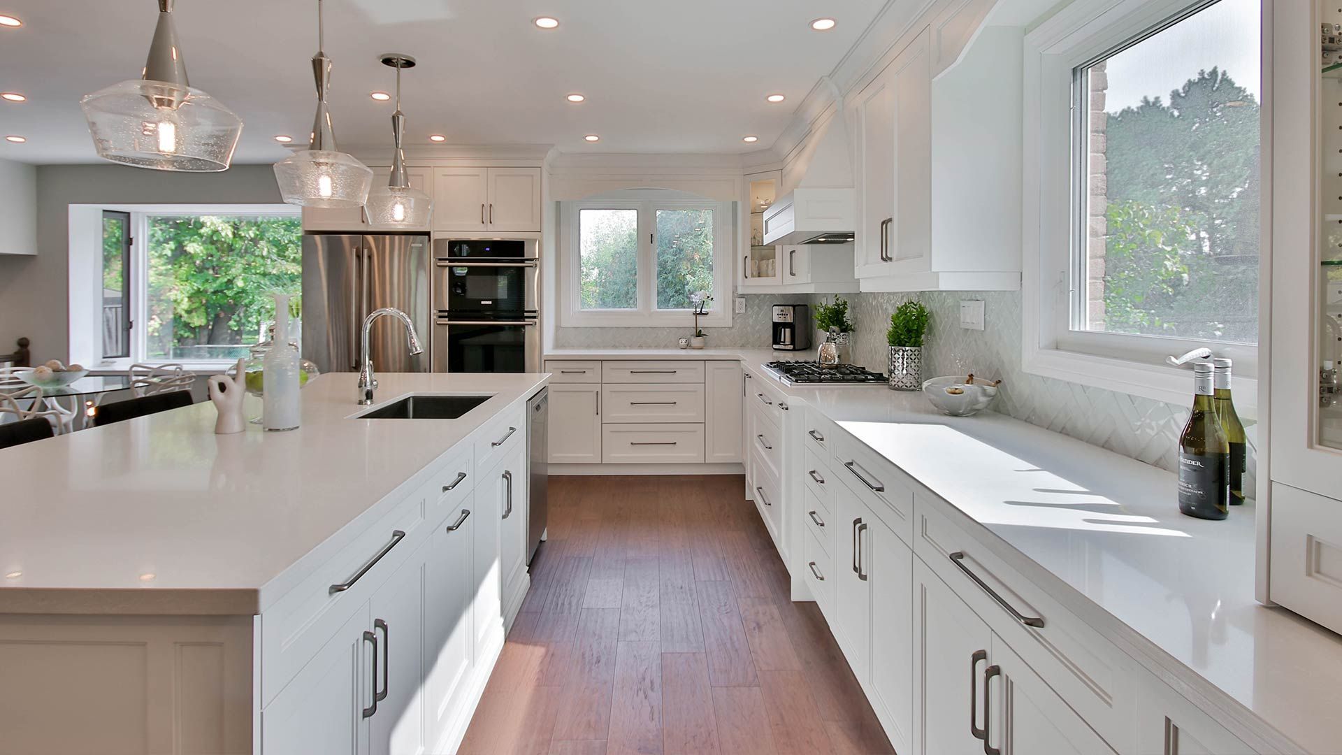 A kitchen with white cabinets , white counter tops , stainless steel appliances and a large island.