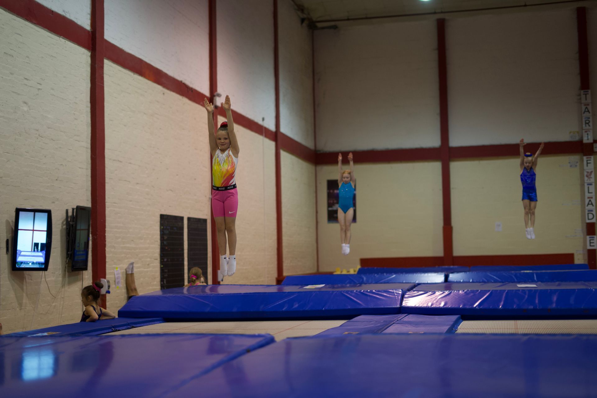 A group of people are jumping on a trampoline in a gym.