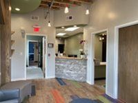Modern office reception area with a stone-front desk, light walls, and multi-colored floor tiles.