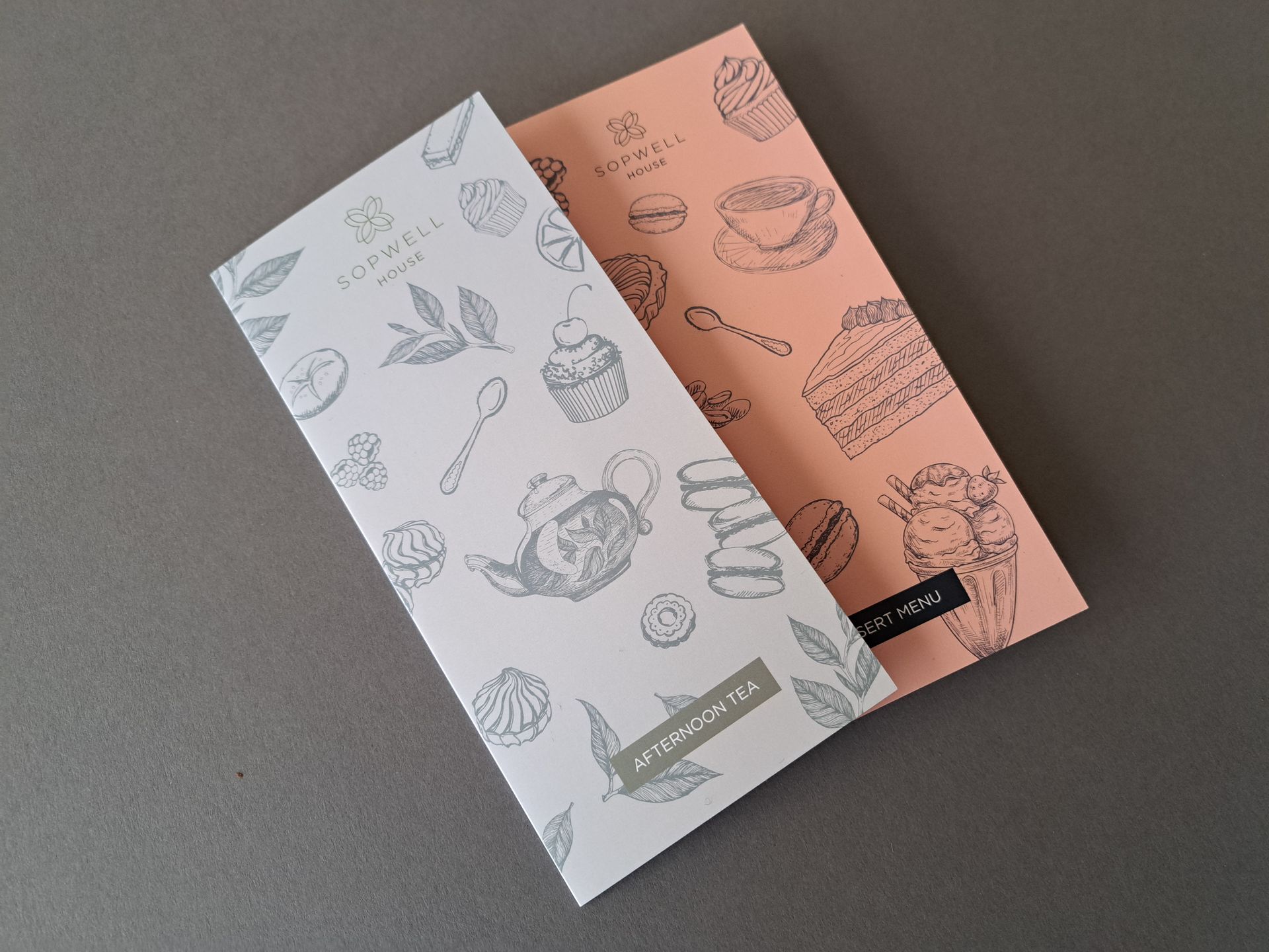 Two patterned brochures, one white and one peach, layered on a gray surface.
