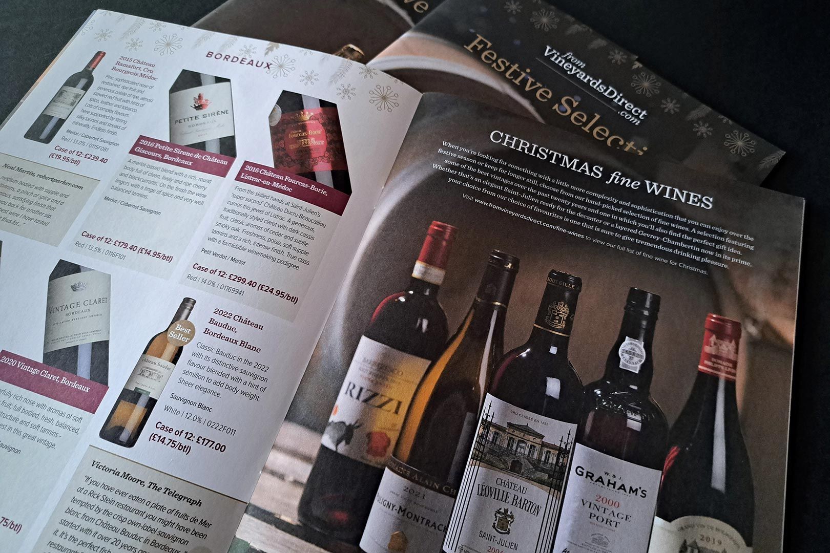 Wine brochures, featuring various wine bottles with descriptions, on a dark surface.