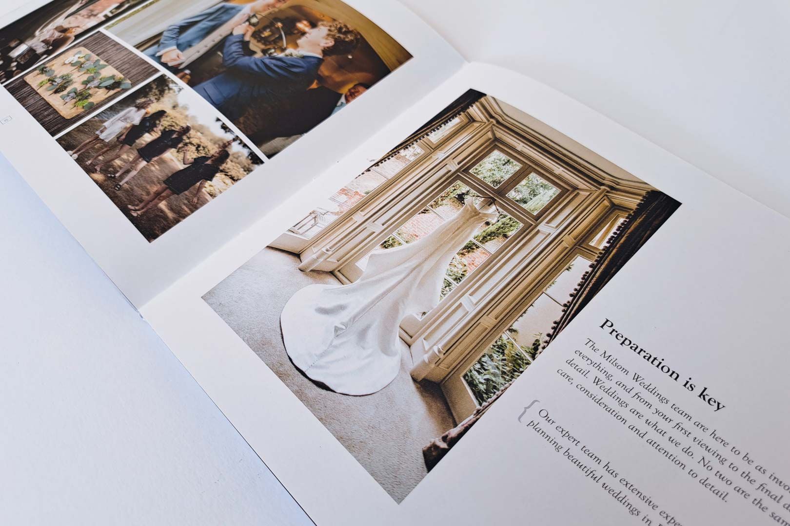 Open photo album with wedding dress hanging near a window.