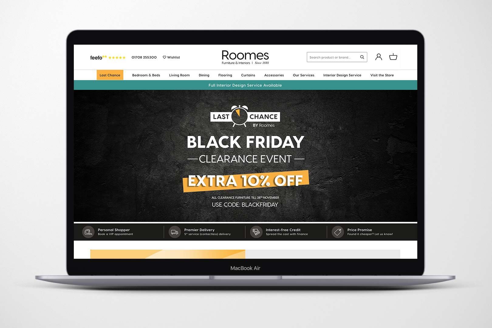 Laptop displaying a Roomes Black Friday sale: Black background with white and gold text.