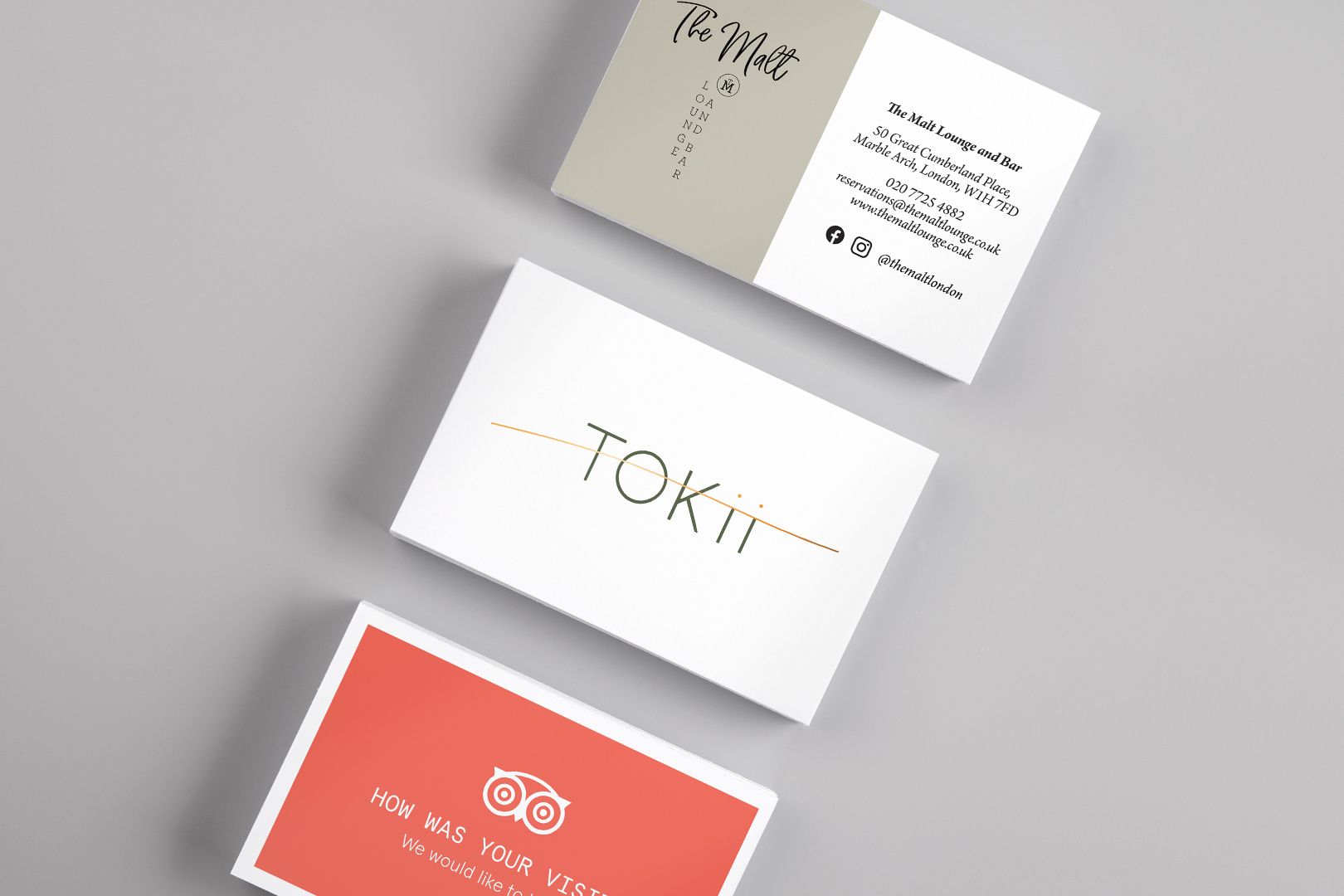 Three business cards on a gray surface: white with gold