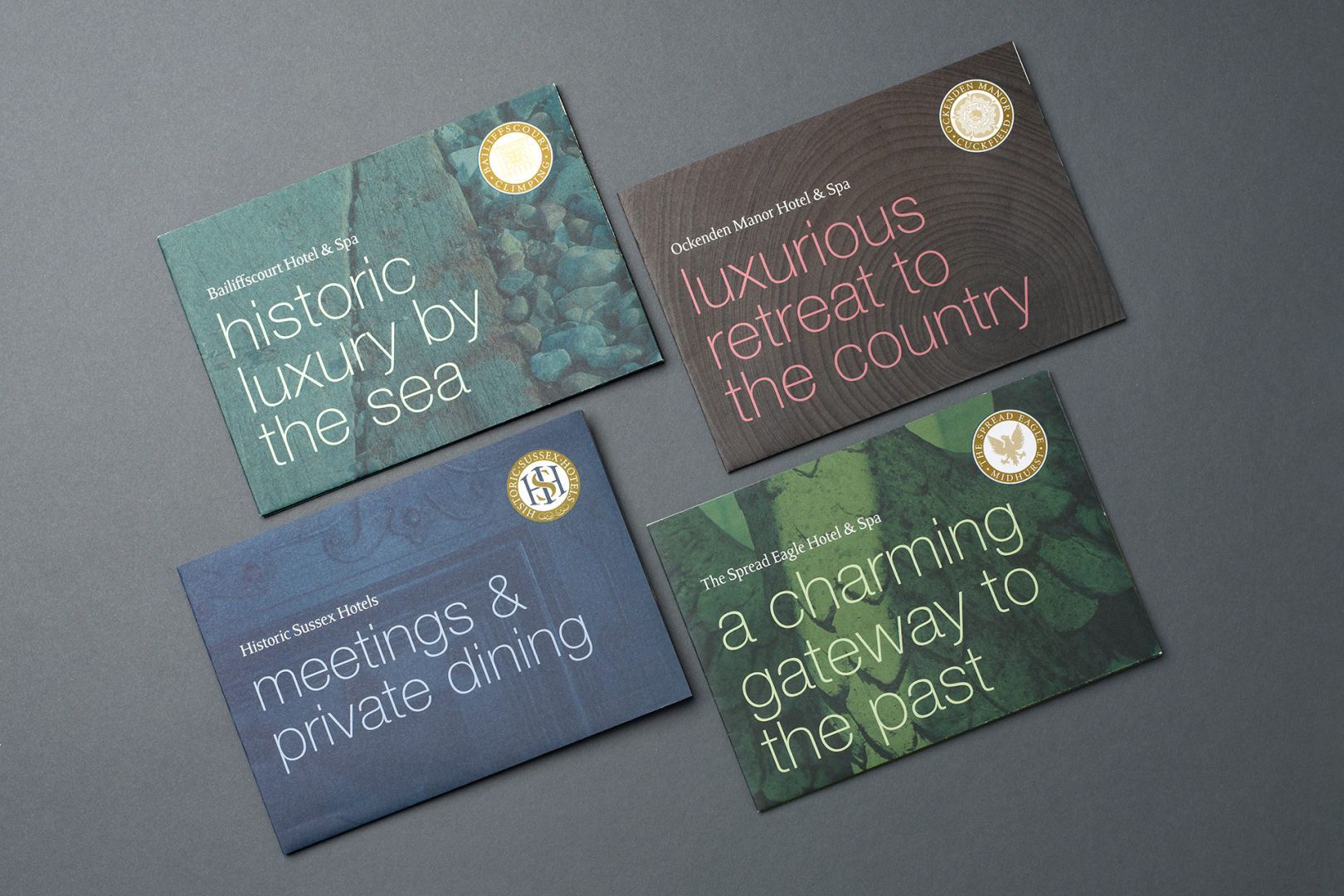 Four business cards, each with text and a gold emblem, various colors, textures and phrases.