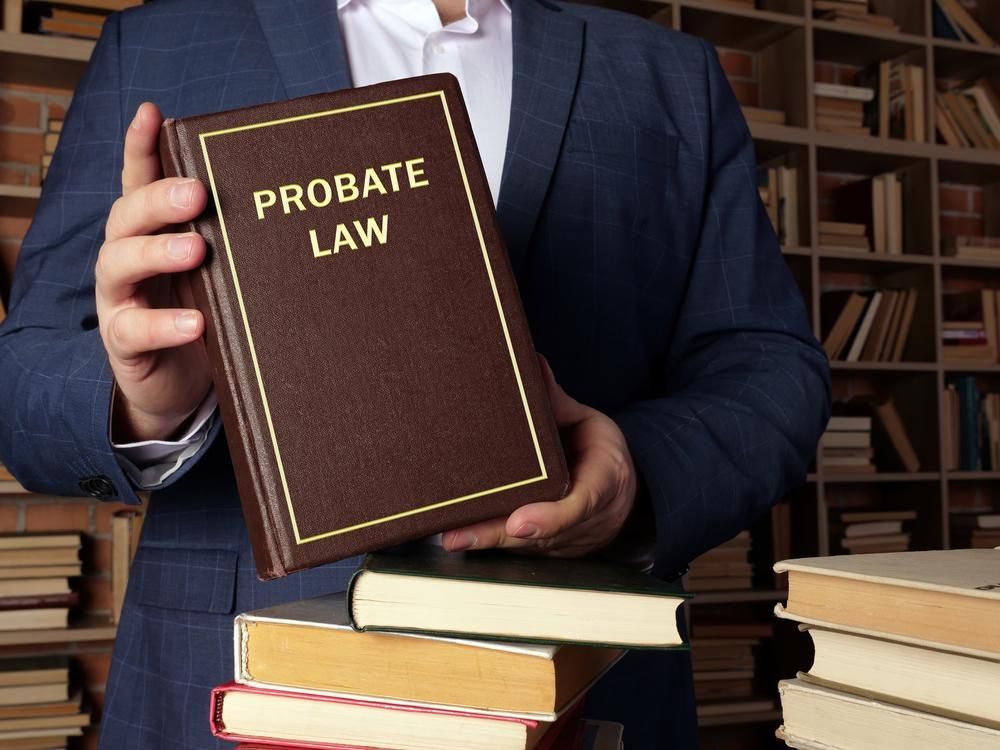 A Man Holding A Book Titled Probate Law — Clarence Valley Legal In Grafton, NSW