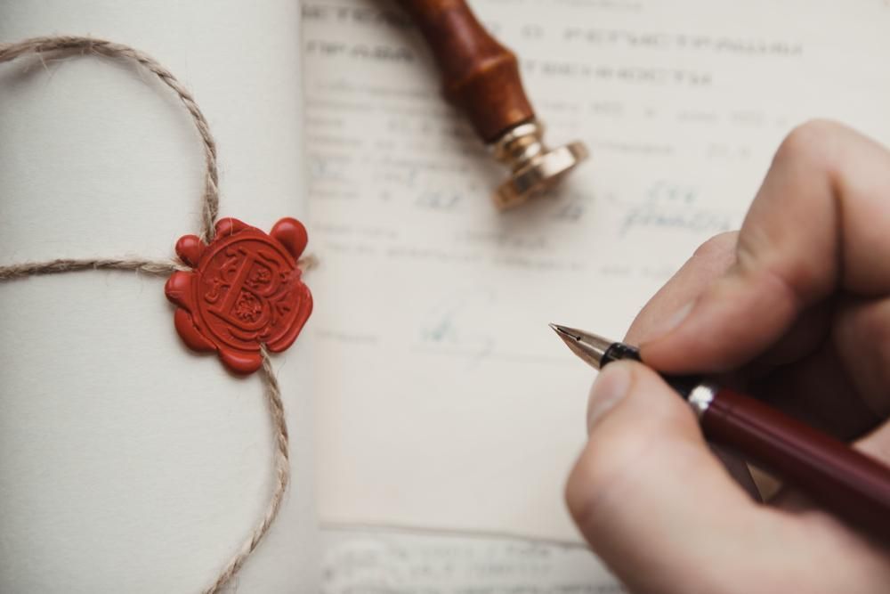 A Person Is Writing On A Piece Of Paper — Clarence Valley Legal In Grafton, NSW