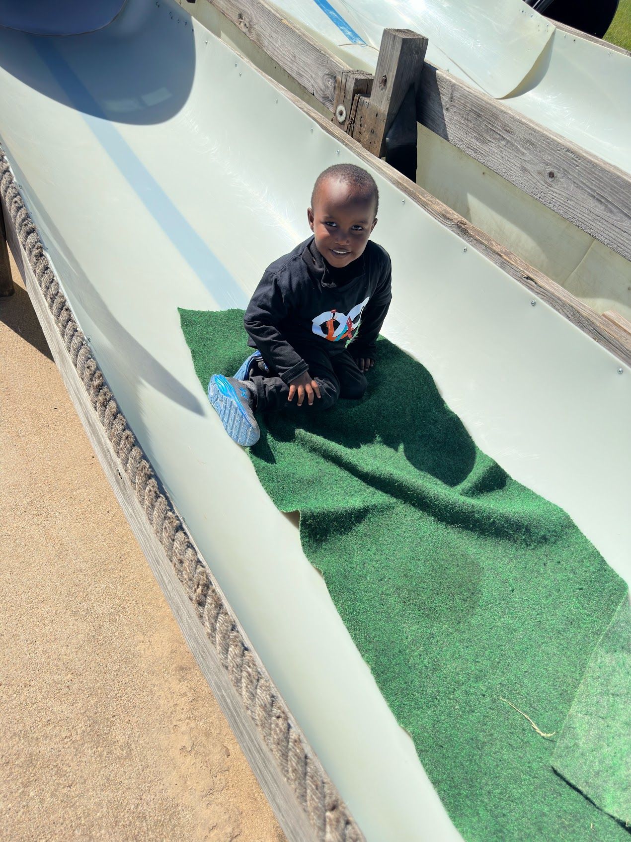 A baby is sitting on the side of a water slide