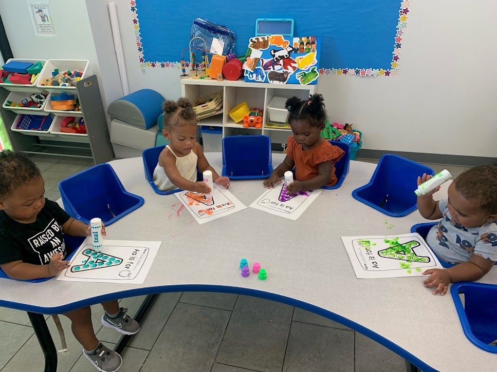 A group of young children are sitting at a table in a classroom.