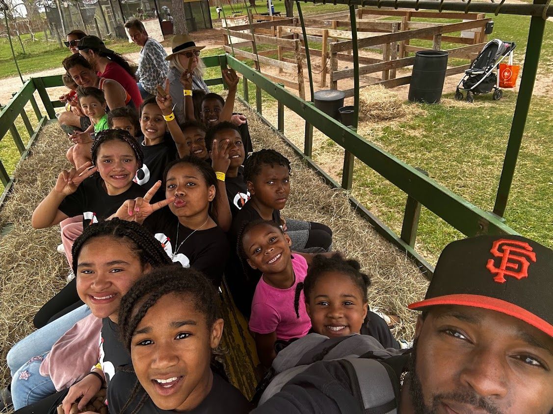 A man is taking a selfie with a group of children on a wagon.