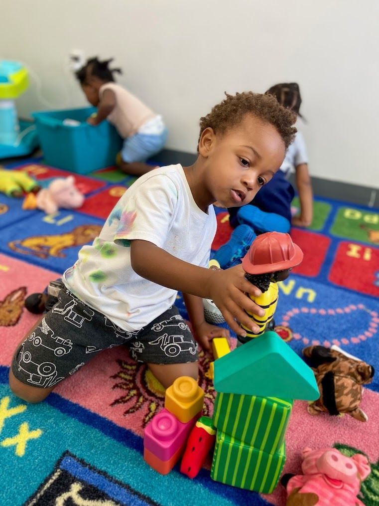 A young boy is playing with blocks on the floor.