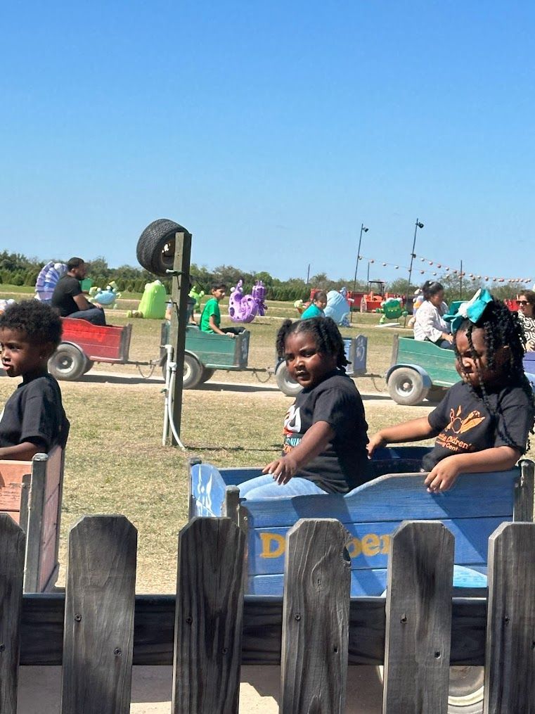 A group of children are riding a toy train in a field.