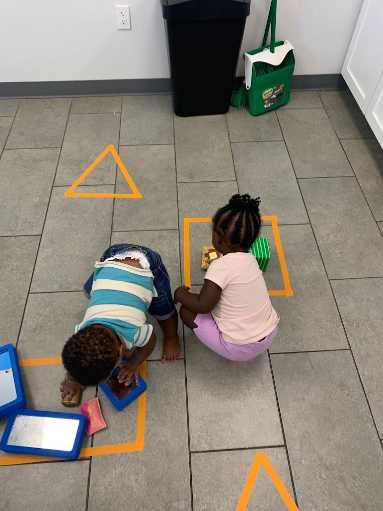 A boy and a girl are playing with tape on the floor