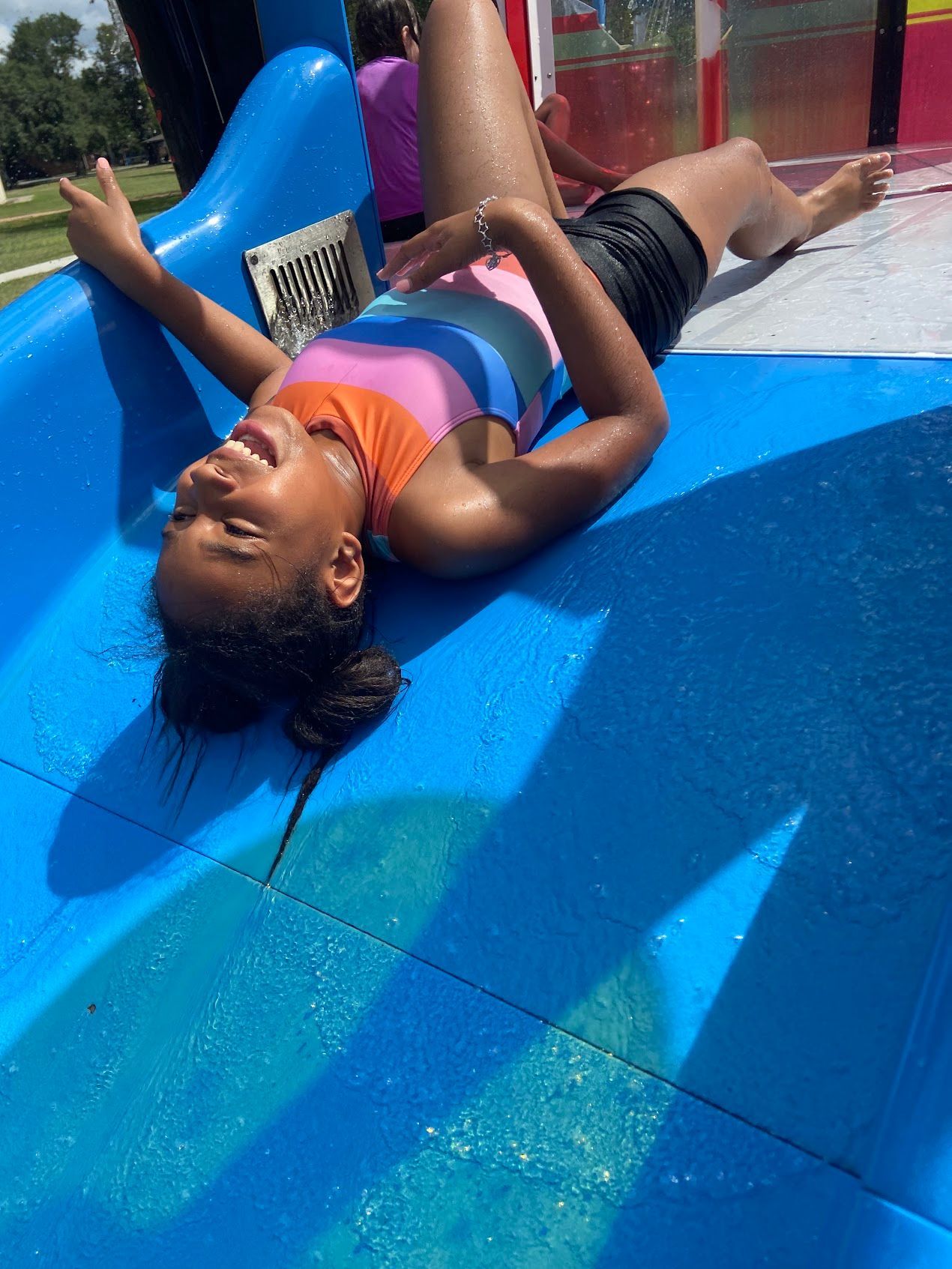 A young girl is laying on top of a blue slide.
