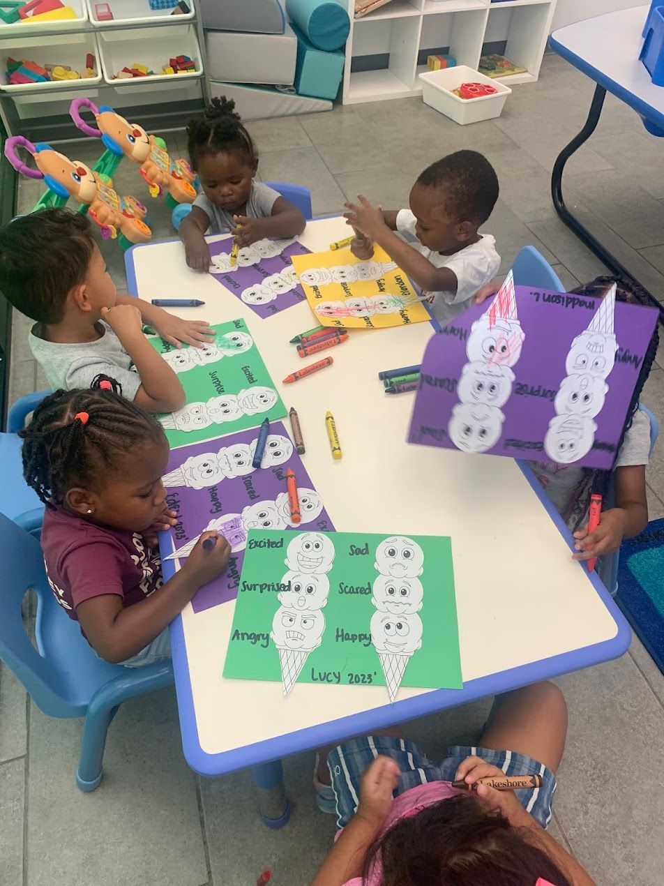 A group of children are sitting at a table making ice cream cones