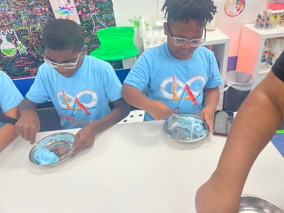A group of children are sitting at a table playing with slime.