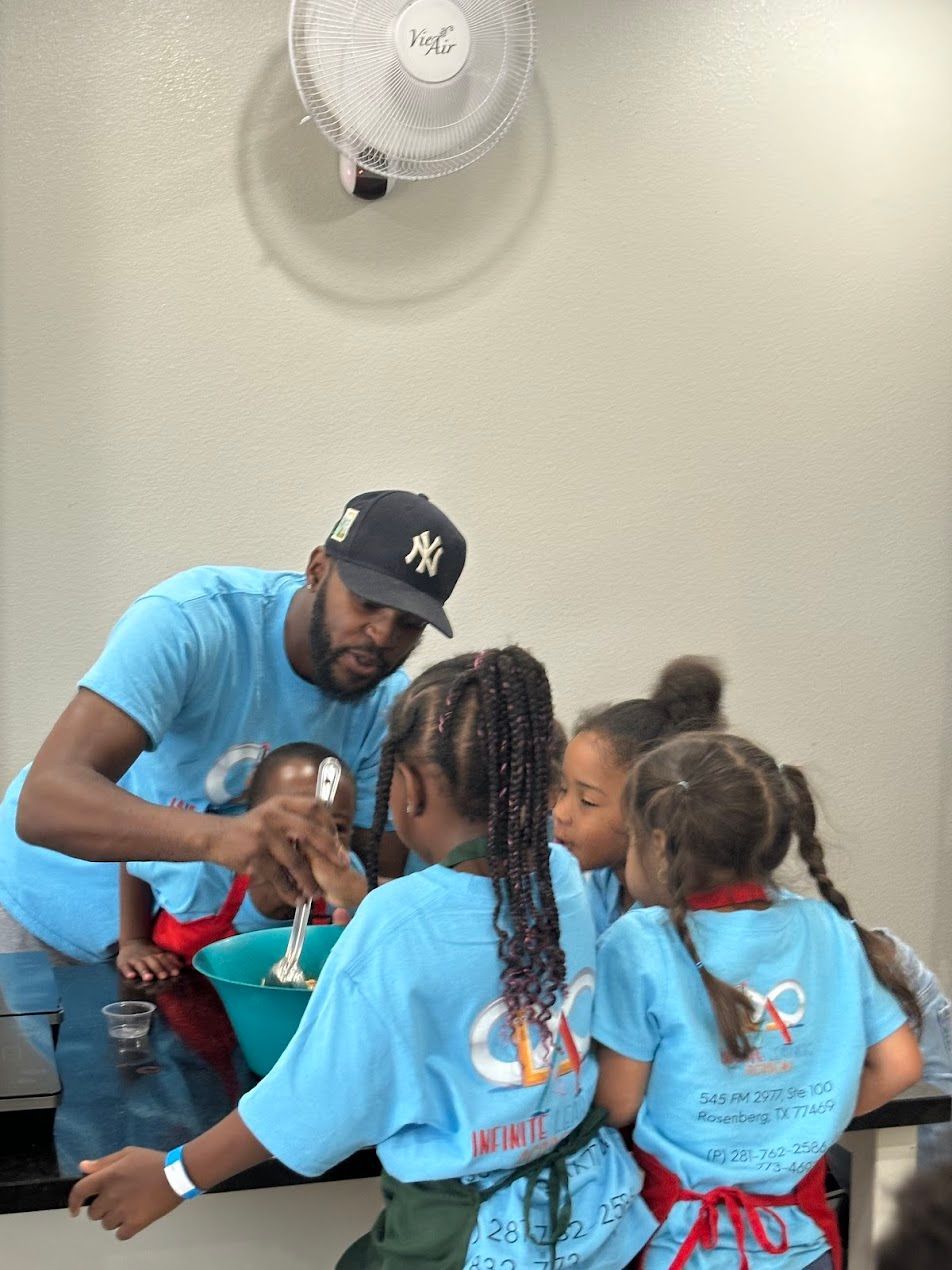 A man in a ny hat is mixing something in a bowl with two little girls