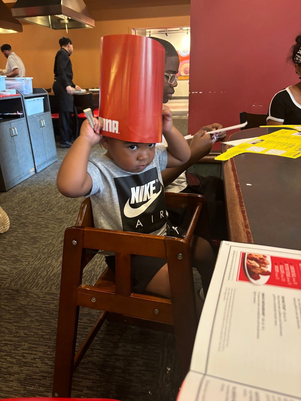 A little boy wearing a chef hat is sitting in a high chair