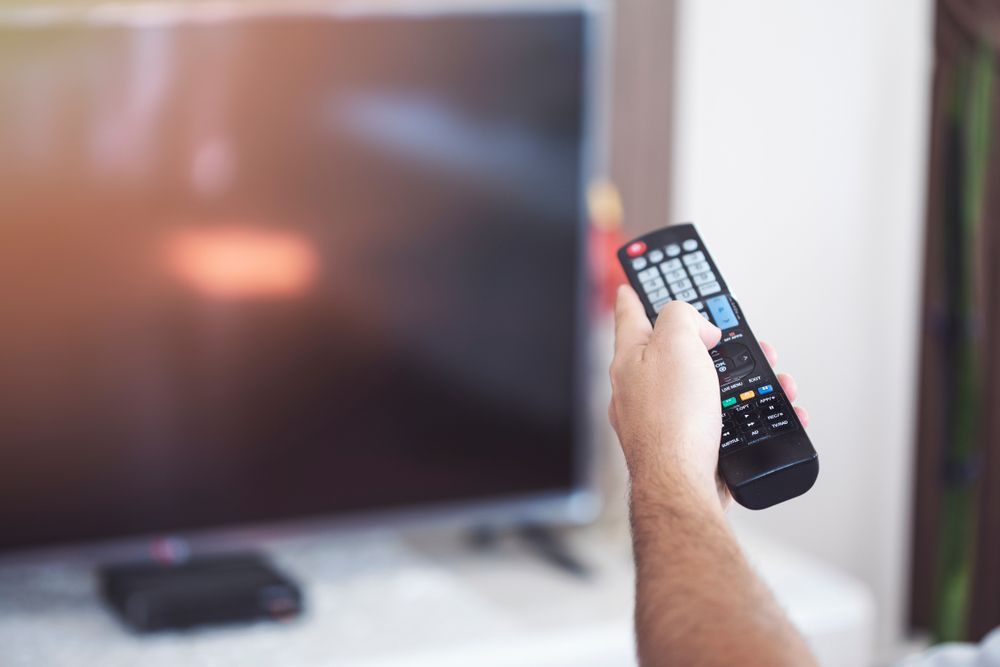A Person Is Holding a Remote Control in Front of A Television  — A1 Antenna Doctor In Port Macquarie, NSW