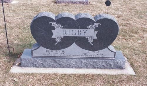 A grey, heart-shaped stone headstone engraved with the name 