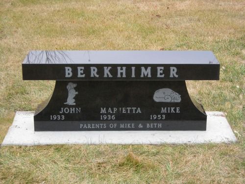 A black granite memorial bench engraved with the surname 