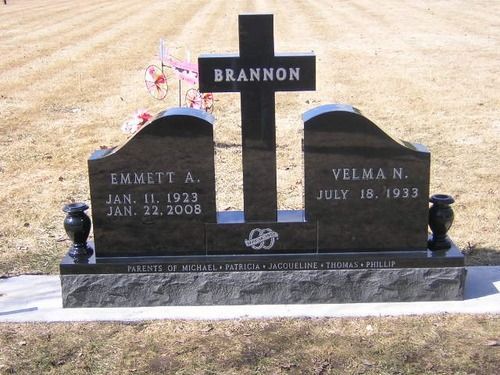 A black granite headstone with a central cross and the name 