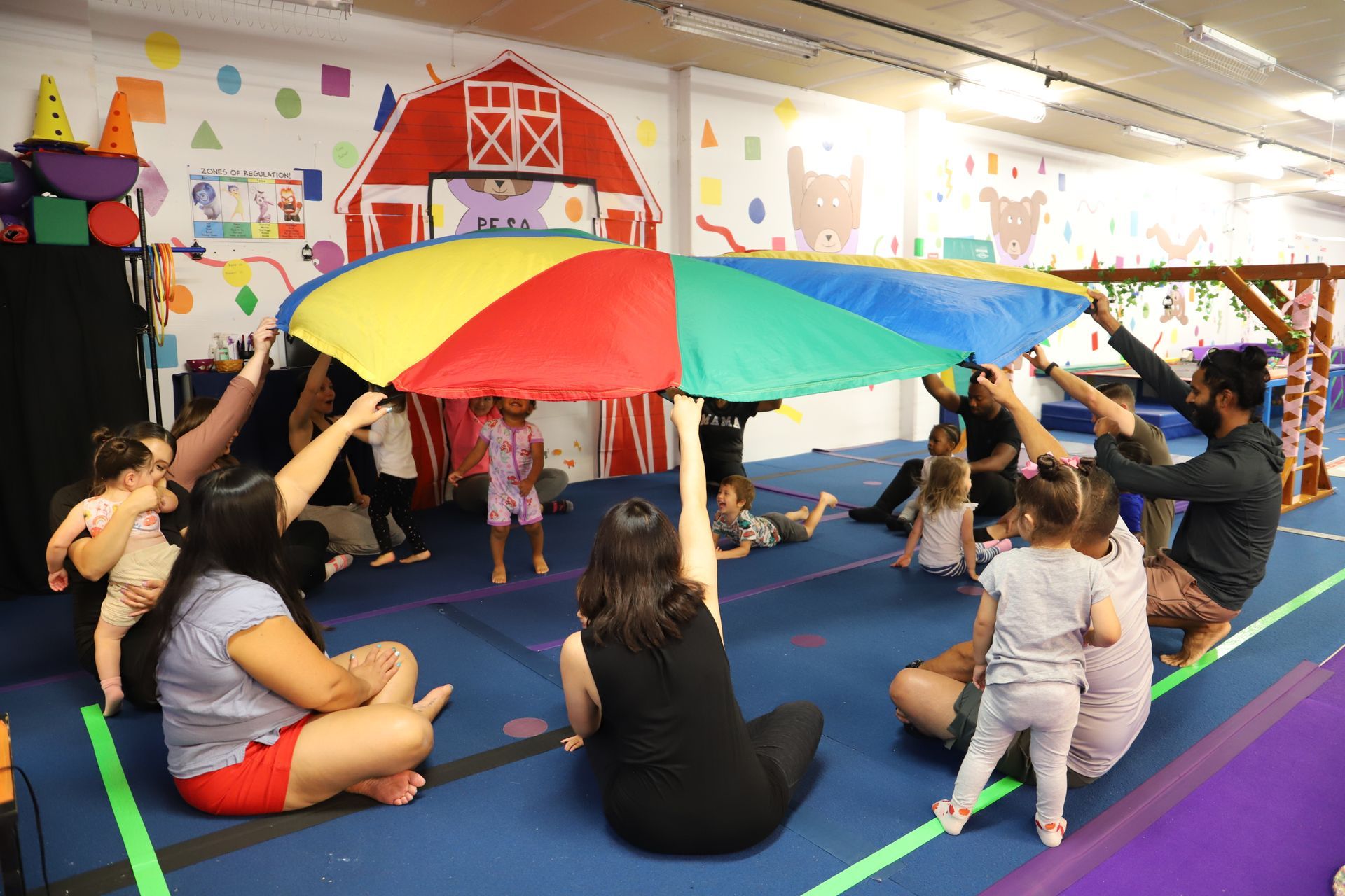 A group of people are sitting in a circle on the floor in a gym.