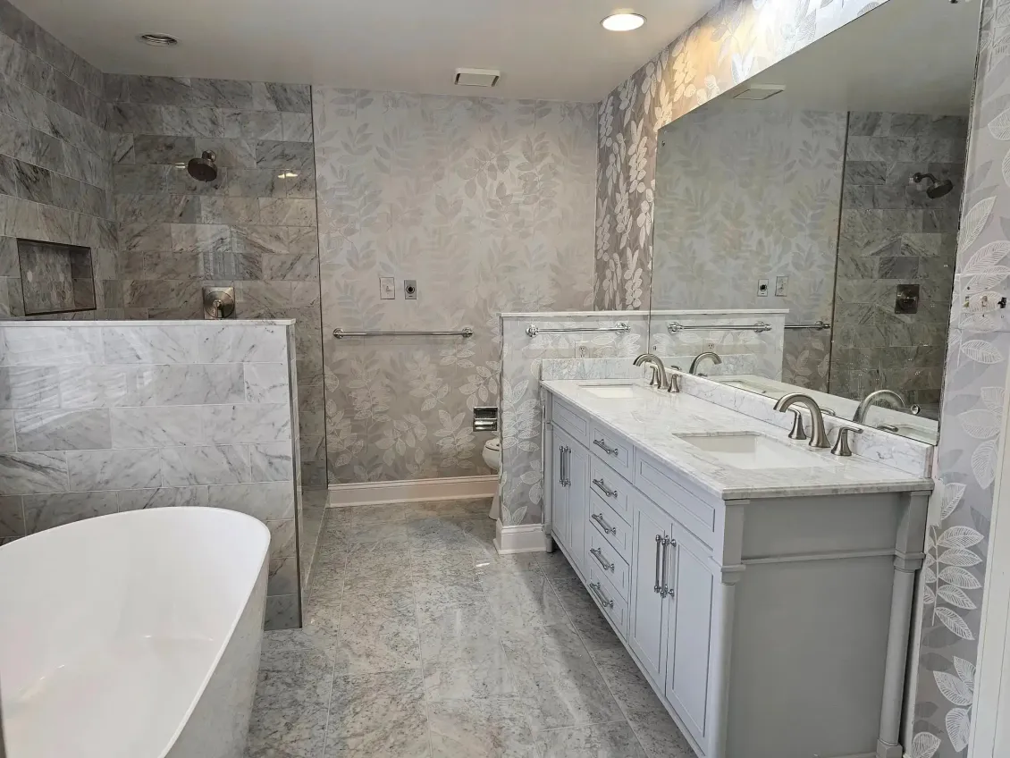 Modern bathroom with freestanding tub, double vanity, and gray stone tile walls and floor