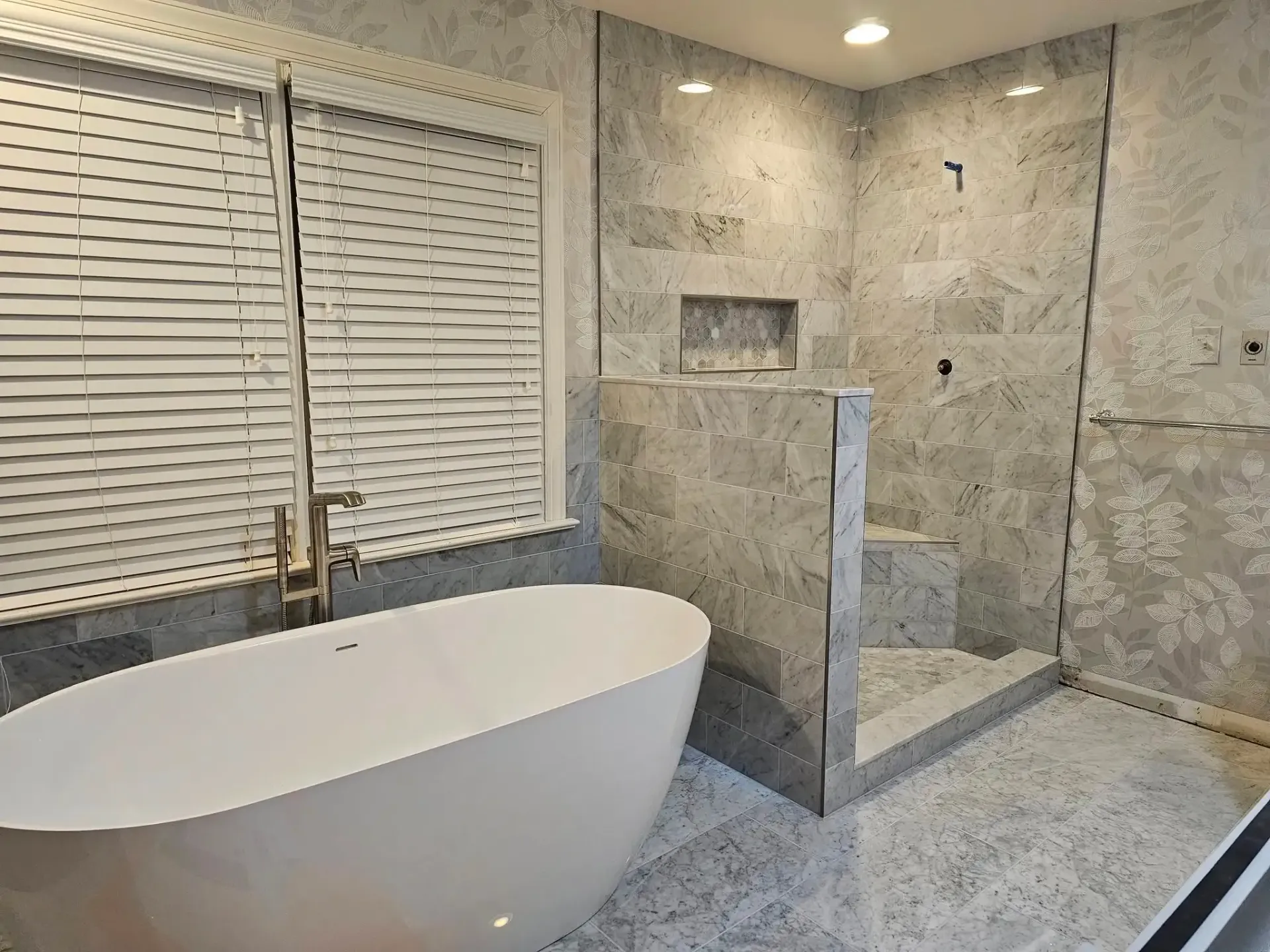 Modern bathroom with freestanding tub, glass shower, and stone tile walls