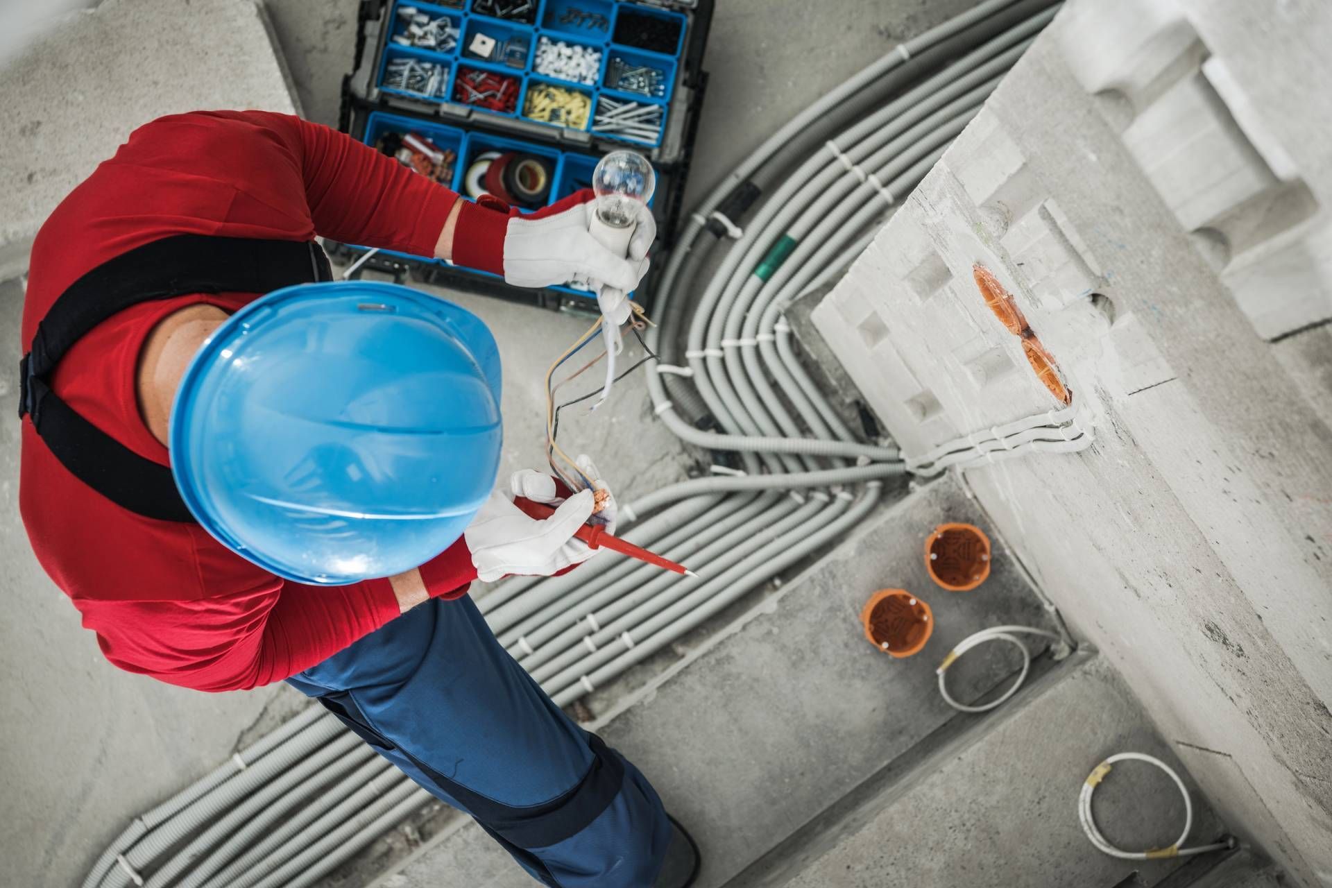 Electrician in a hard hat wiring electrical conduit.