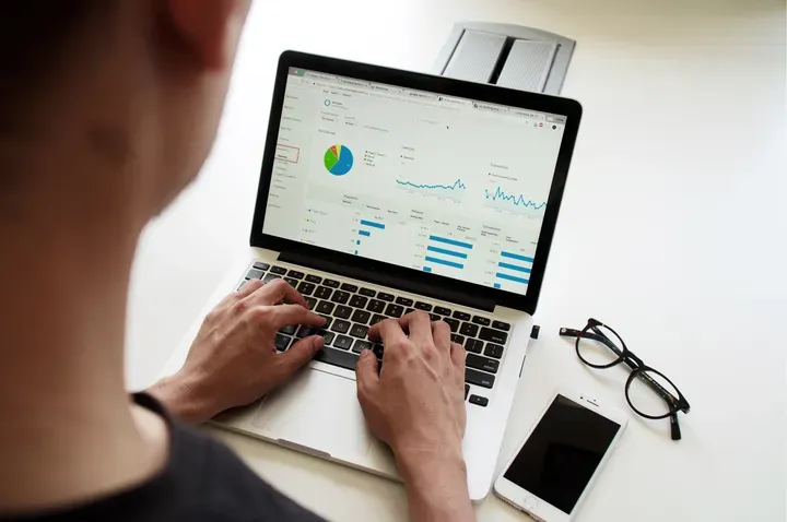 Um homem está digitando em um laptop com um gráfico na tela.