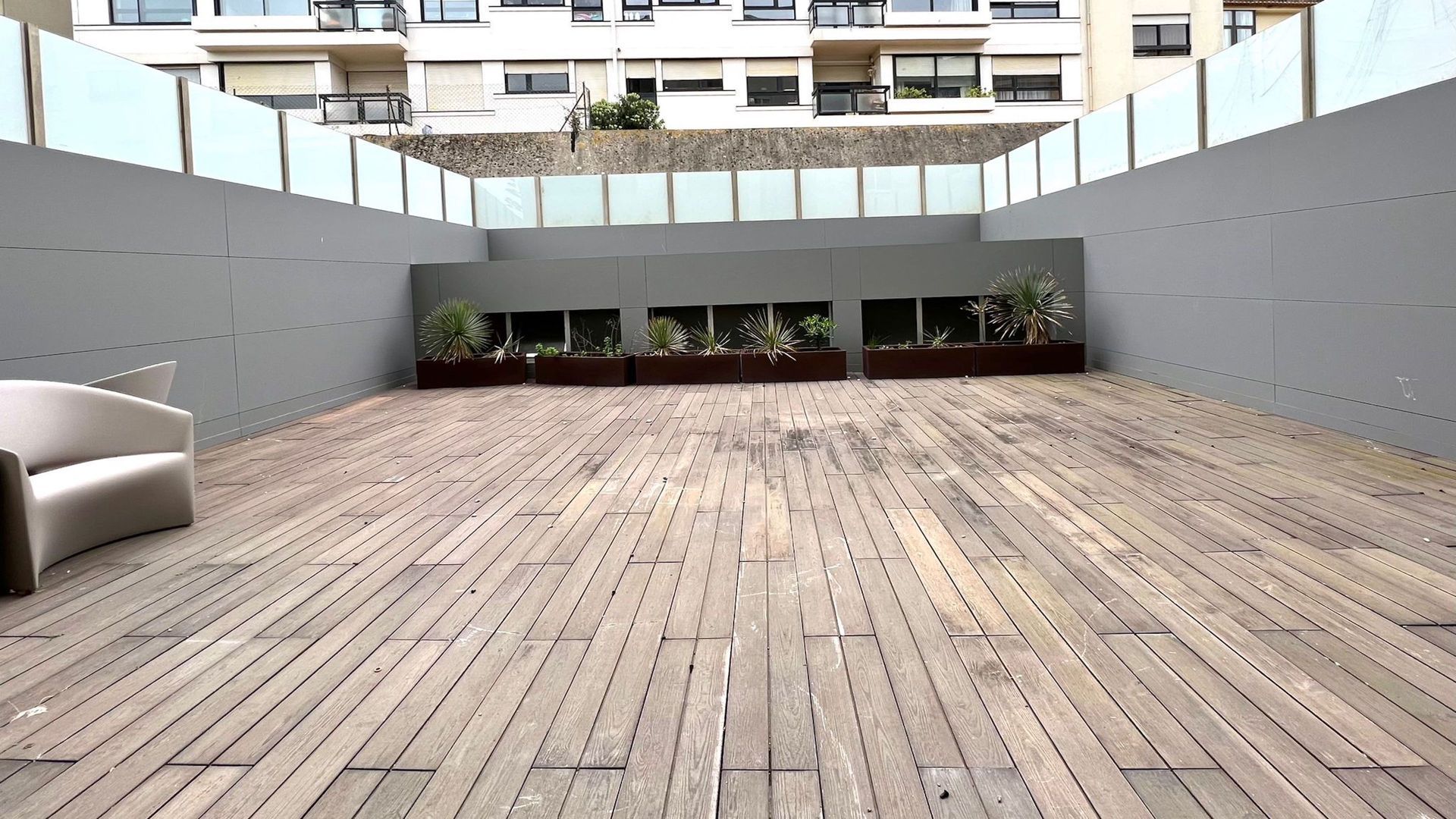 Um deck de madeira vazio com uma cadeira e um prédio ao fundo