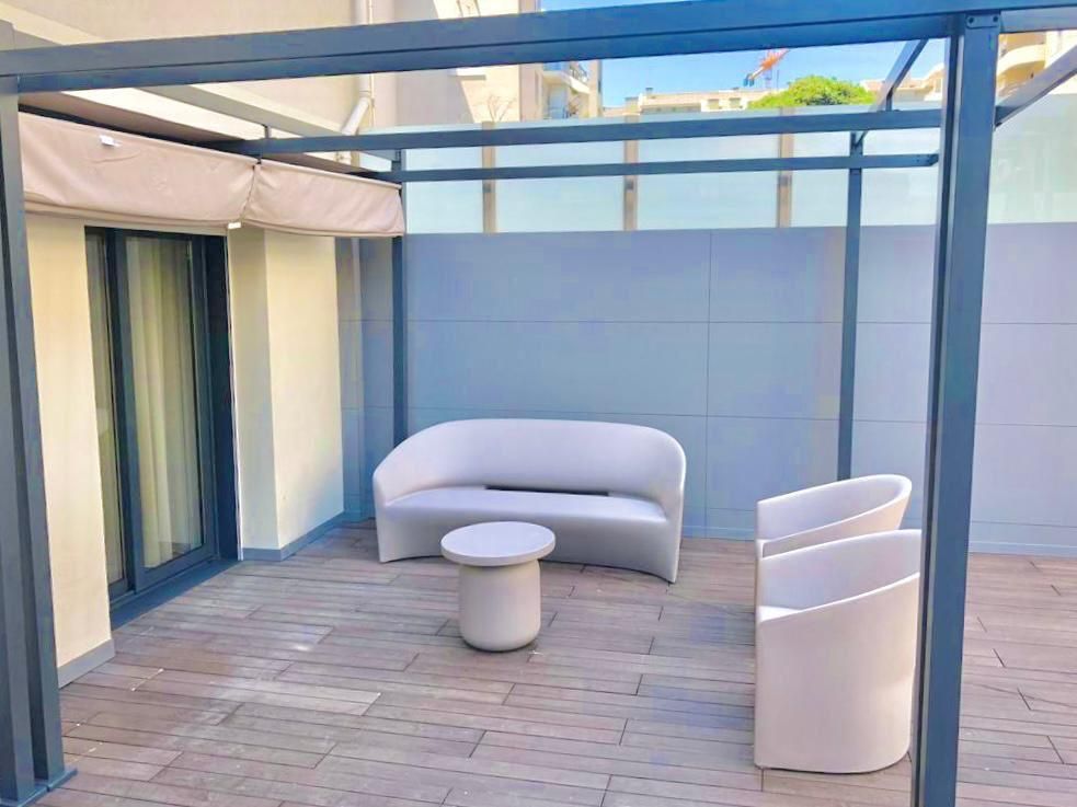 Um pátio com um sofá, cadeiras e uma mesa sob uma pérgola.