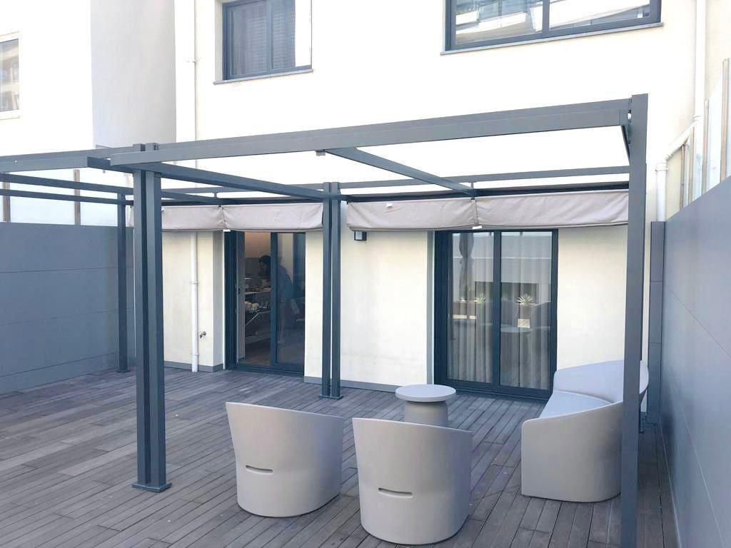 Um pátio com cadeiras e uma mesa sob uma pérgola