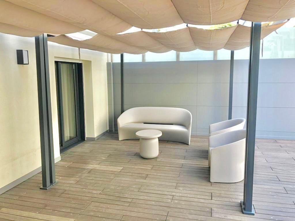 Um pátio com um sofá, cadeiras e uma mesa sob um dossel.