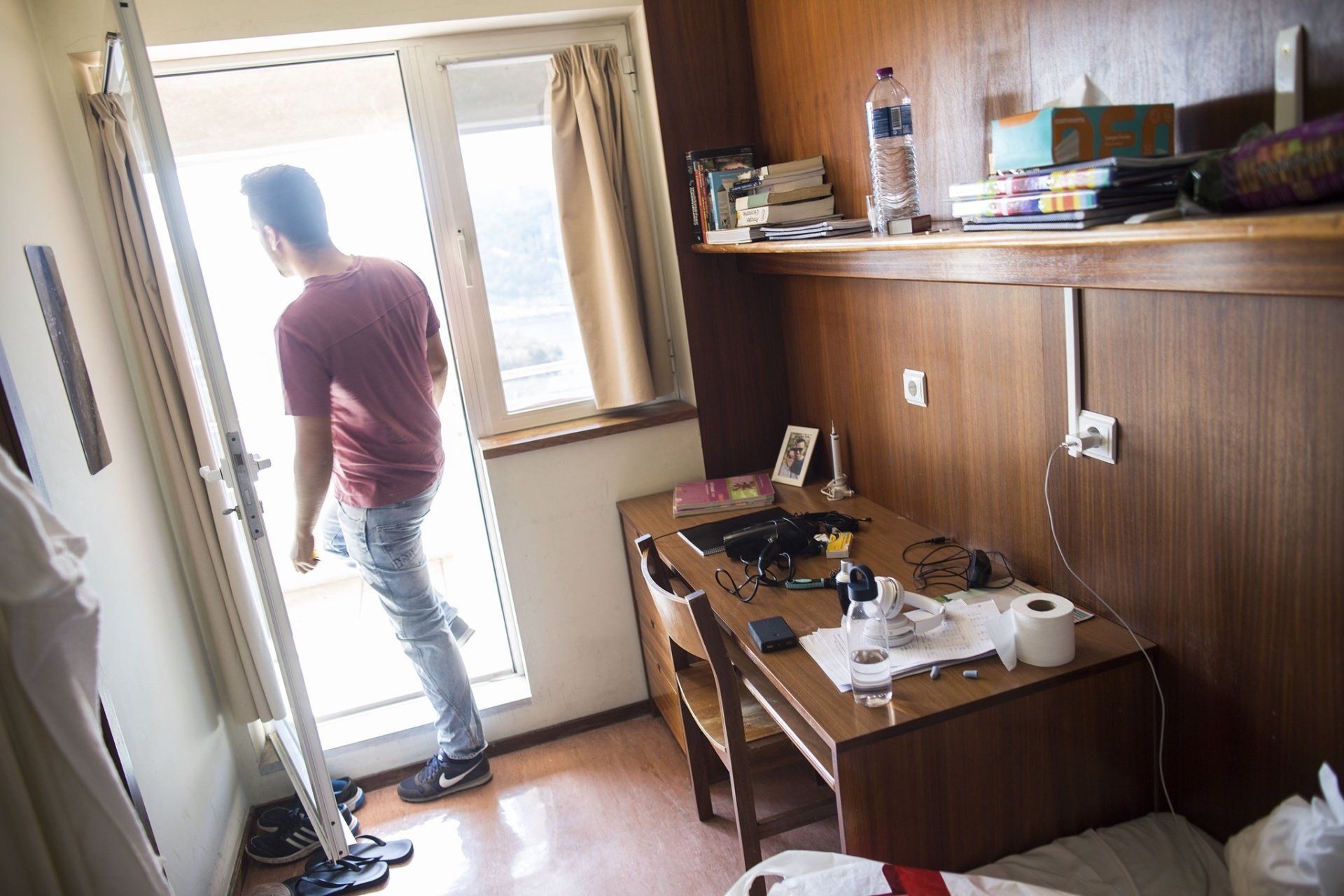 Um homem está parado em uma sala olhando para fora da porta.