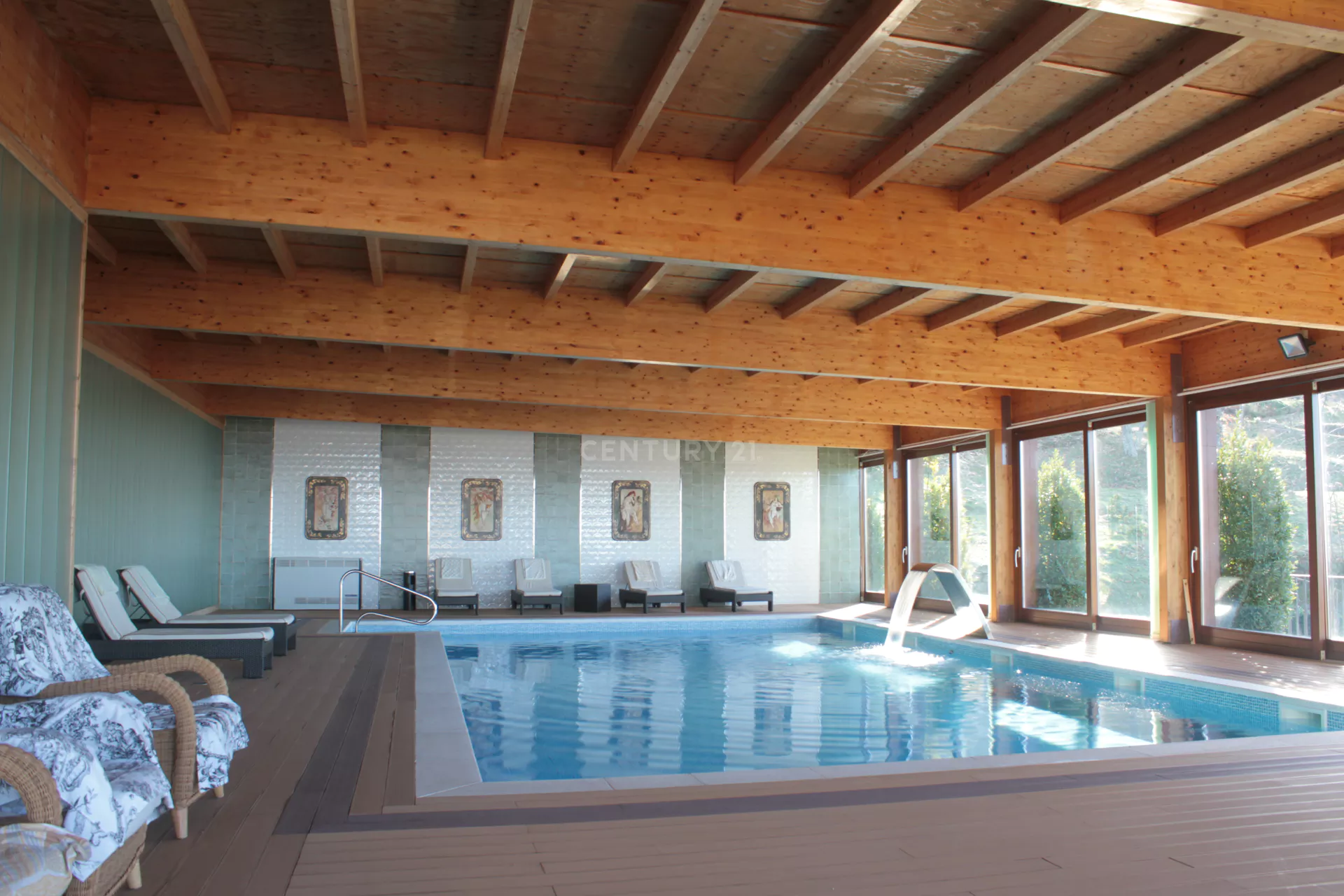 Uma grande piscina coberta com cadeiras e teto de madeira